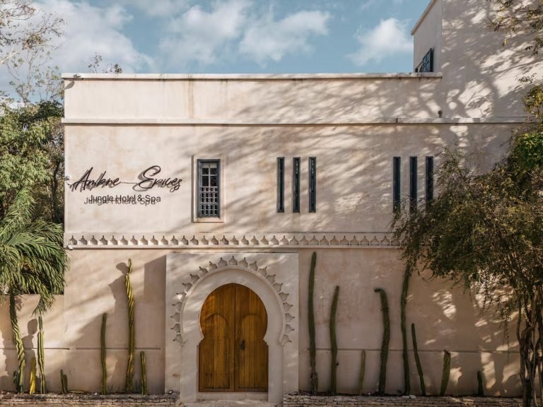 Whitewashed Moroccan-style facade with an arched doorway at Ambre et Epices villa in Tulum