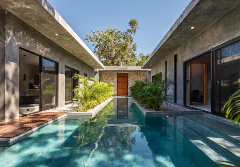 Pool and palms in front of the minimalist dark facade of Santo villa in Tulum