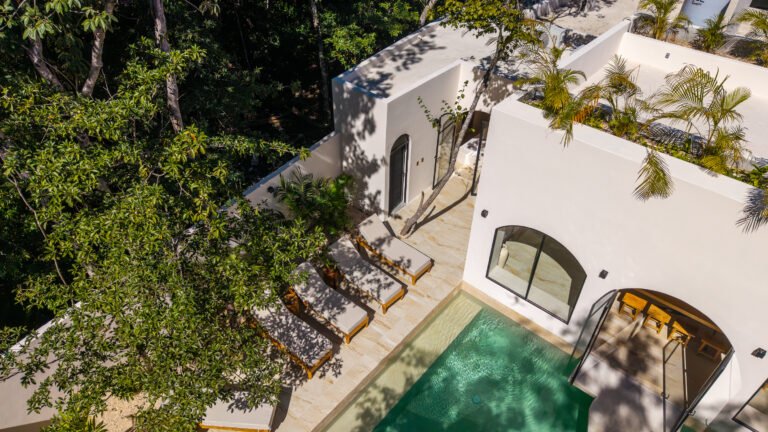 Aerial view of a private villa with a pool, terraces and sun loungers surrounded by jungle canopy in Tulum, Mexico