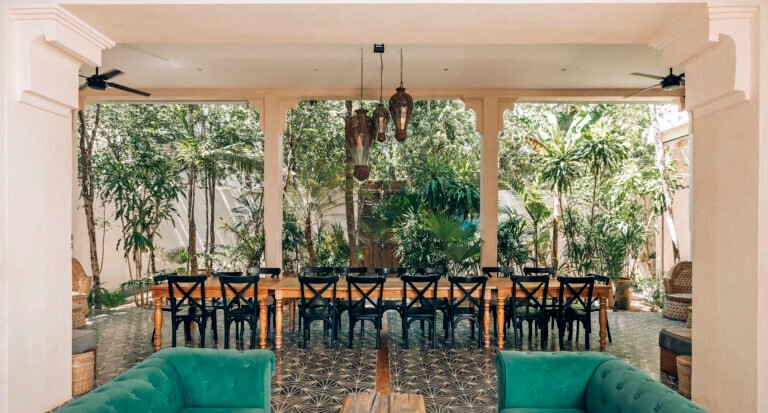 Long dining table set for sixteen guests on the covered terrace of Yum Kaax, an eight-bedroom villa in Tulum