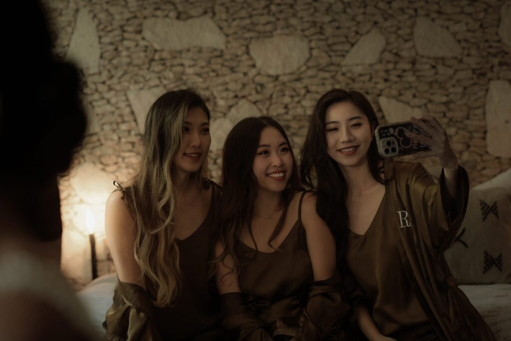 Three guests in silk robes taking a photo together in a Tulum villa bedroom