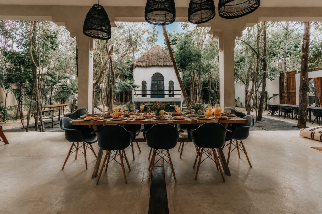 Long dining table set for twelve under the jungle canopy of a private Tulum villa